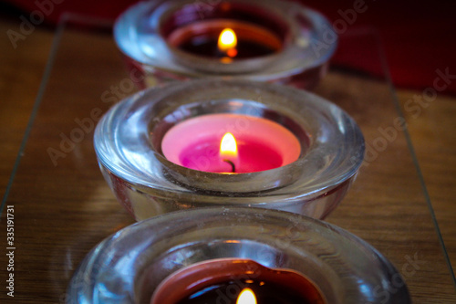 Three Tea Candles In Small Candlesticks.