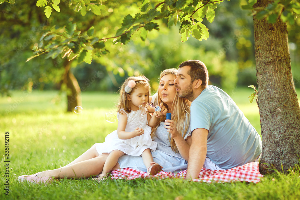 Happy family is hugging while sitting in the park. Happy family is hugging while sitting in the park.
