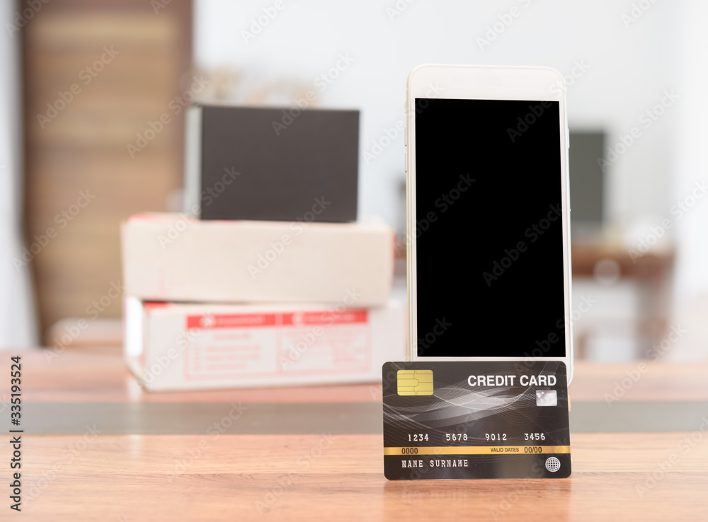Mobile phone and credit card on wood table at home,online shopping while Covid-19 Mobile phone and credit card on wood table at home,online shopping while Covid-19