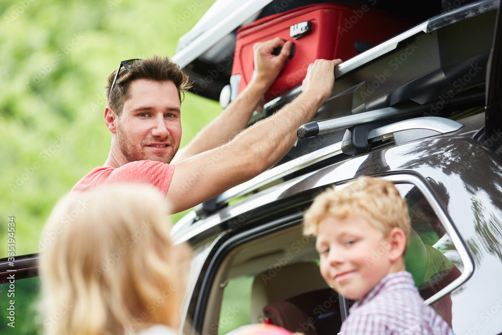 Familie verstaut Gepäck in der Auto Dachbox Familie verstaut Gepäck in der Auto Dachbox