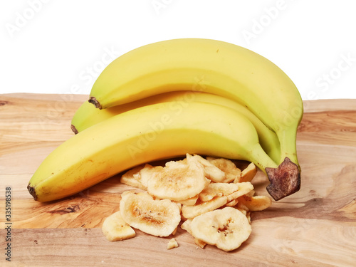 Dried slides and fresh bananas on a wooden board and white background.