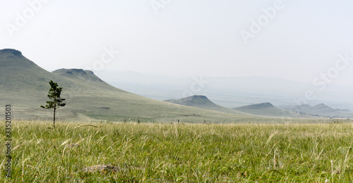 Mountains and hills in the early, foggy morning against a gray sky. Russia, Buryatia