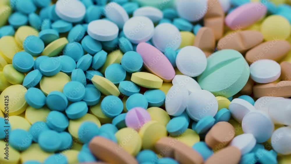 Multi-colored tablets sprinkled on yellow and blue nutritional supplements Multi-colored tablets sprinkled on yellow and blue nutritional supplements