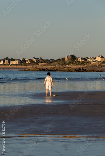  A woman practicing yoga on the beach of Saint Malo in the glow of the setting sun. Brittany, France