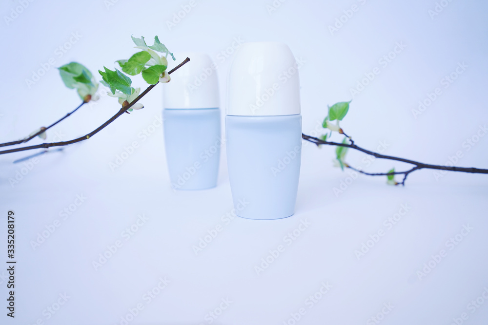 concept of protection against sweat and smell, Two roller antiperspirants with green branches on a light background