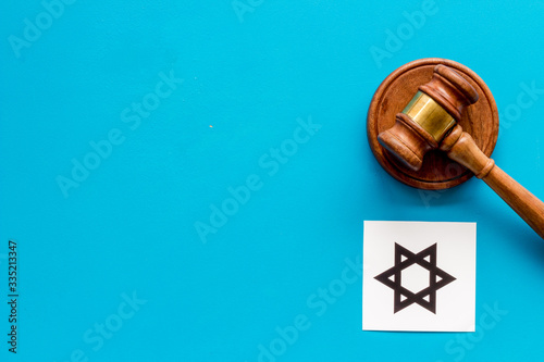 Star of David sign - religion Judaisim symbol - near gavel on blue table top view. Religious conflict concept. Copy space photo