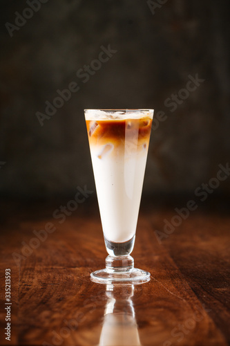 delicious cold chocolate ice cream milkshake with syrup in a long glass, dark wooden background, side view, vertical