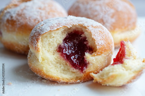 Fresh baked and garnished with powdered sugar german doughnuts - Berliner or Krapfen - on white table.