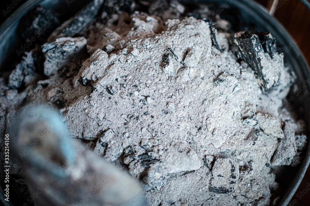 Fototapeta premium Charcoal and ash are cleaned from the home fireplace in an iron galvanized bucket.