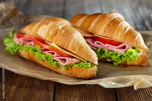fresh croissant sandwiches with ham and cheese on wooden background