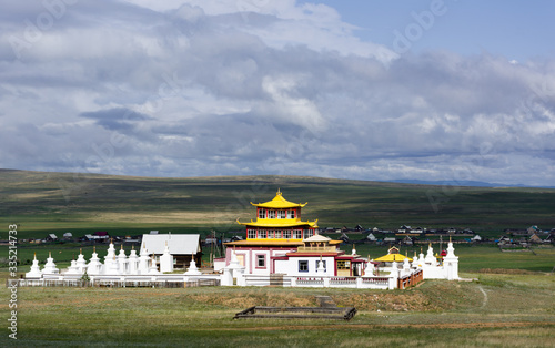 Datsan in the sun on a cloudy day against a dark sky. Russia, Buryatia