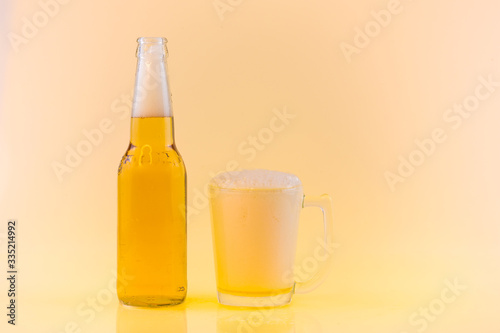 Bottle and Glass of cool beer with foam, clipping path, bubbles in a drink, on abstract orange background.