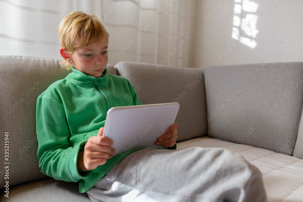 Young handsome boy using digital tablet on the couch at home Young handsome boy using digital tablet on the couch at home