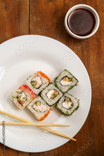 A set of rolls with dill and salmon with soy sauce, ginger and chopsticks.