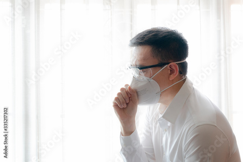 Asian man get cough during wear safety google and N95 surgical mask to protect COVID-19 for other people. Stay home, Work from home, Social Distance Concept.