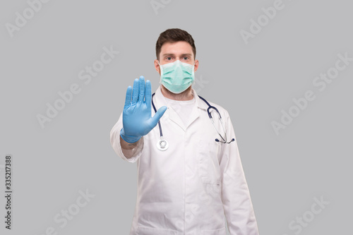 Male Doctor Showing Stop Sign. Doctor Wearing Medical Mask and Gloves. Focus on Hand. Stop Virus Concept