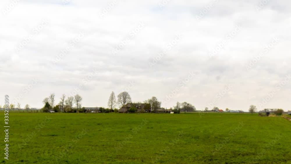 Clouds passing over idyllic farm in rural landscape in the Netherlands Clouds passing over idyllic farm in rural landscape in the Netherlands