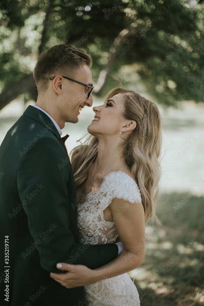 Portrait of a lovely bride and groom embrace, kiss and hug each other. Couple in love in the bosom of nature . Handsome groom and beautiful blonde bride posing in the forest. Modern dress and suit Portrait of a lovely bride and groom embrace, kiss and hug each other. Couple in love in the bosom of nature . Handsome groom and beautiful blonde bride posing in the forest. Modern dress and suit