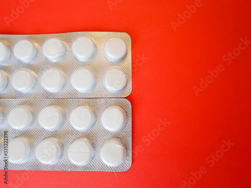 white pills on a red background. snow-white round antibiotics against viruses. photo