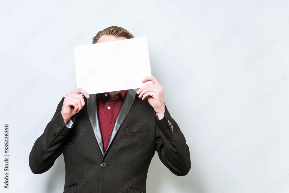 European businessman in red polo shirt and blazer holding blank A4 poster paper covering his head, in front of his face. Place for text, copy space European businessman in red polo shirt and blazer holding blank A4 poster paper covering his head, in front of his face. Place for text, copy space