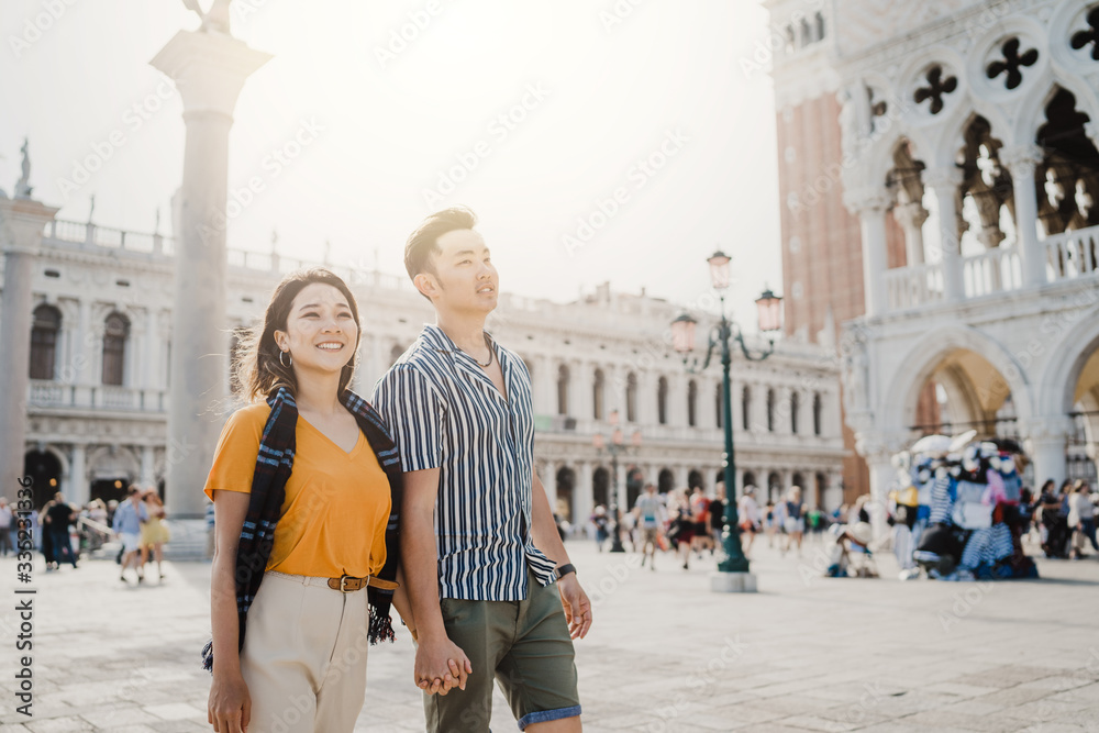 Loving couple in Venice, Italy - Millennials walking in the city - Asian young people on vacation in Italy