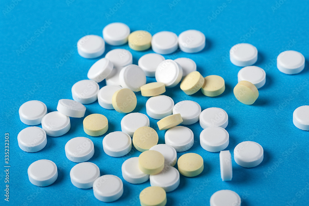 Many scattered tablets in white and yellow on a blue background.