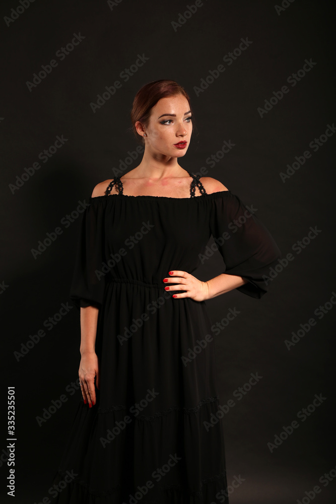 Fototapeta premium Studio portrait of pretty woman in black dress on dark background