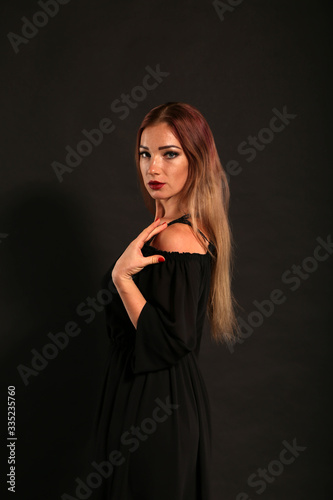 Studio portrait of pretty woman in black dress on dark background
