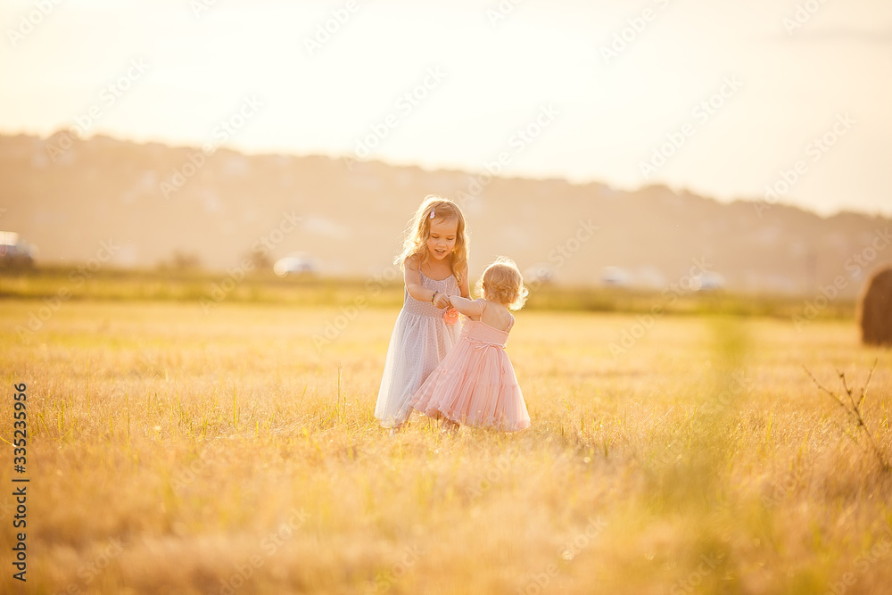 little girls spin together on sloping wheat field