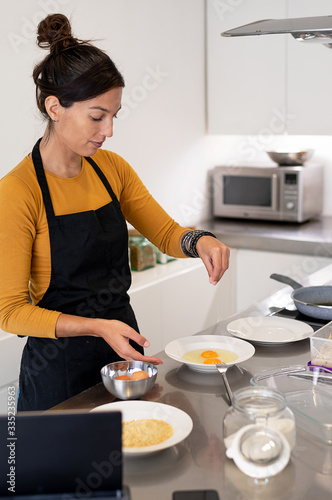 Young woman with an apron cooking an omelette for breakfast in a modern kitchen
