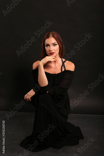 Studio portrait of pretty woman in black dress on dark background