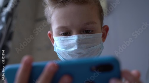 A child in a medical mask looks at the phone