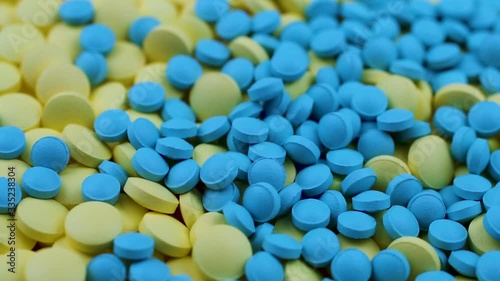 Blue pills fall on yellow ones on top and rotate on a table in a pharmacy