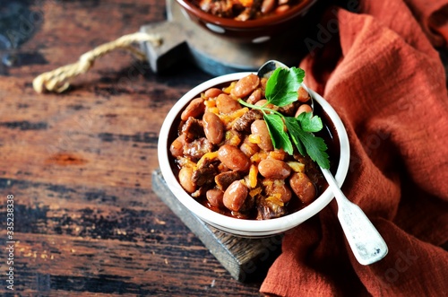 Beef stew with beans, tomatoes and vegetables on a dark wooden background