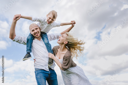  Family on a walk in a field with green grass and blue sky, early spring, good weather, happy family, white clothes
