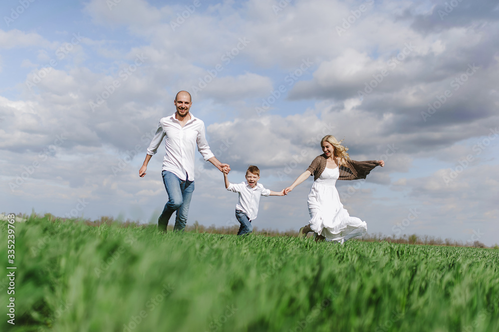  Family on a walk in a field with green grass and blue sky, early spring, good weather, happy family, white clothes