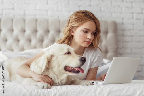 Beautiful teen girl with golden retriever dog in a bed © Natalia Chircova