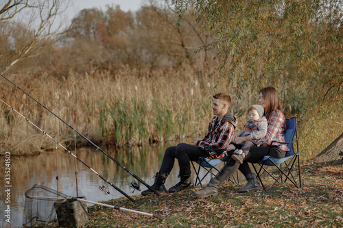 Family by the river. Guy in a red shirt. Father with little son in a fishing.