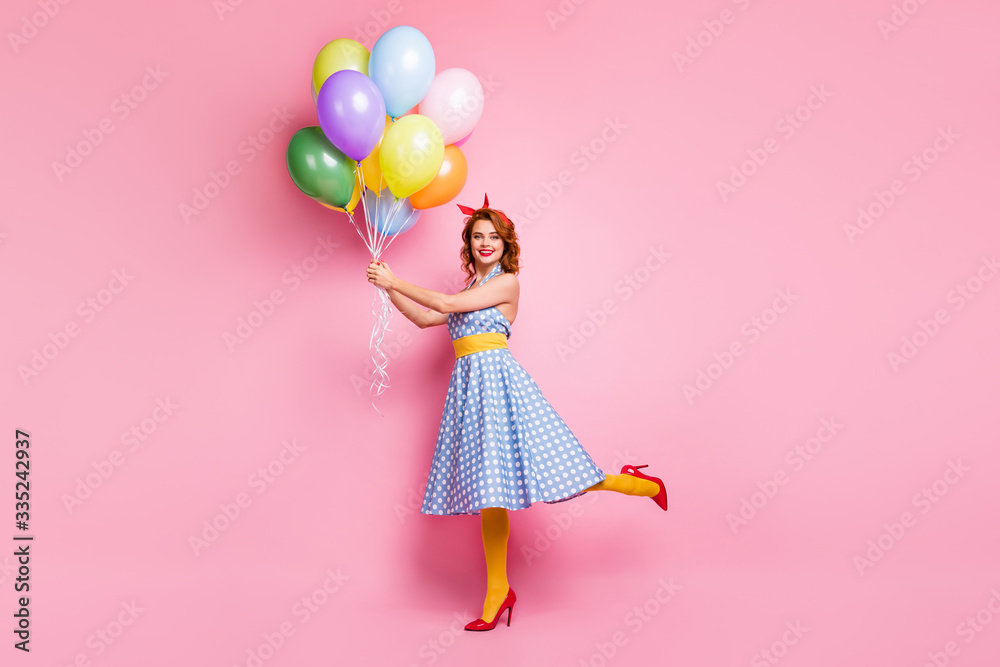 Full length photo of positive fifty style vogue lady fun walk hold many colorful bright air baloons fly wear blue high-heels skirt yellow oantyhose red footwear isolated pink color background Full length photo of positive fifty style vogue lady fun walk hold many colorful bright air baloons fly wear blue high-heels skirt yellow oantyhose red footwear isolated pink color background