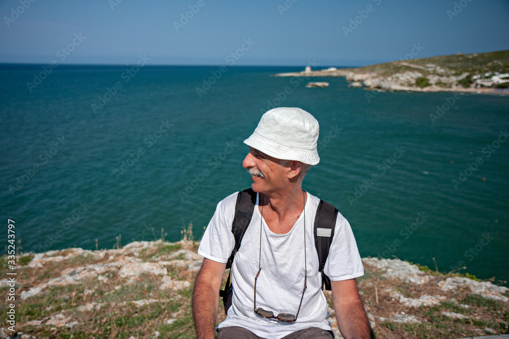 Tourist observes the enchanting seascape on the Gargano cliff in Italy.