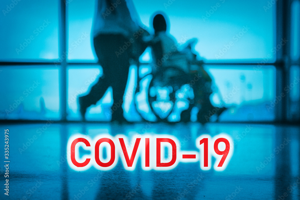 COVID-19 billboard red text on blue medical hospital background with doctor walking with disabled patient in wheelchair. - obrazy, fototapety, plakaty 