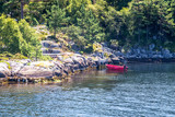 Typical scandinavian rocky shore with a red boat