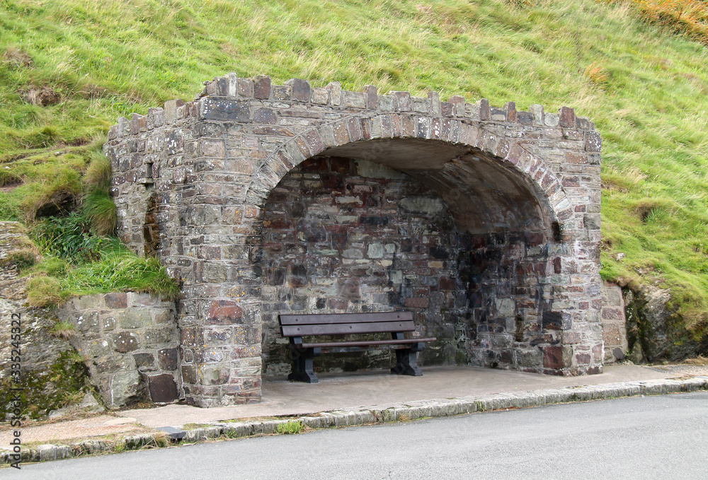 A Wooden Bench Seat in a Stone Built Wind Shelter.