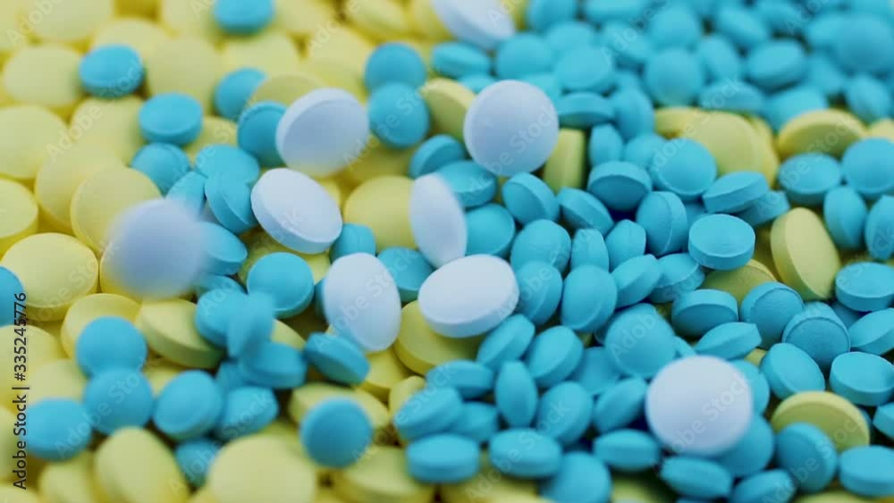 White homeopathic remedies fall on yellow and blue pills scattered on the table White homeopathic remedies fall on yellow and blue pills scattered on the table