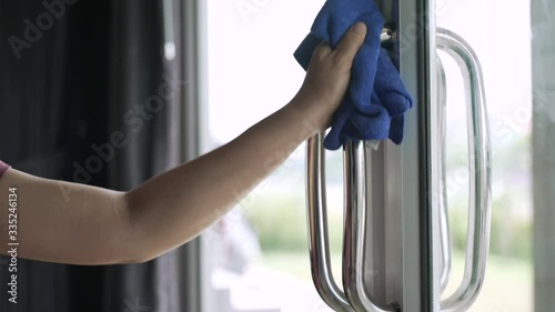 Cleaning building entry door handle with spray alcohol and wiper cloth