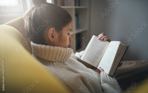Close up of pretty girl in sweater reading favorite book photo