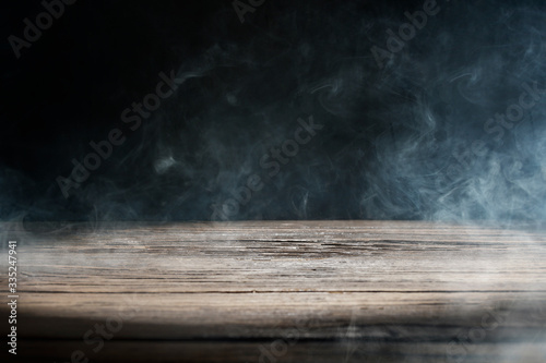 An old wooden table on a black background with smoke