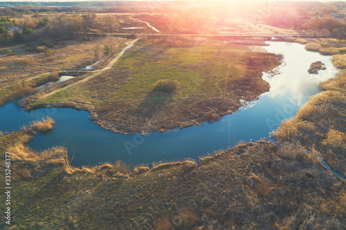 Aerial view of the countryside at sunset light. Winding river on the meadow in the evening. Beautiful rural nature landscape in the evening.