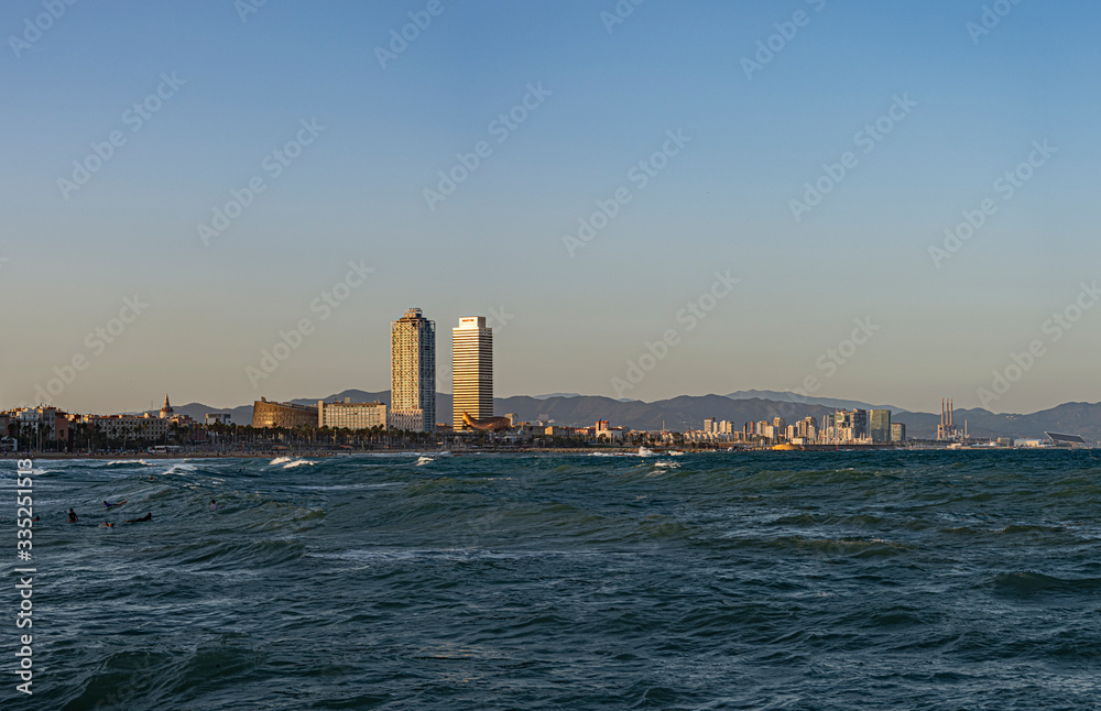 Fototapeta premium beach of the capital city, the sea is mixed with waves, the sky with clouds and tall buildings with skyscrapers in the background, there is a famous hotel