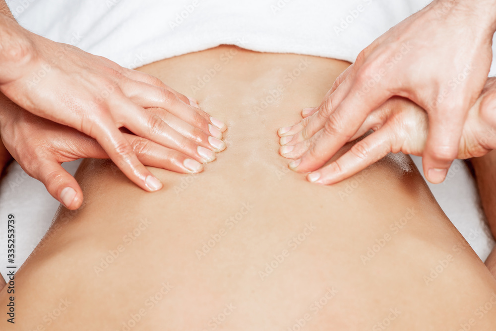 Man receiving back massage in four hands of two male therapists close up. Man receiving back massage in four hands of two male therapists close up.